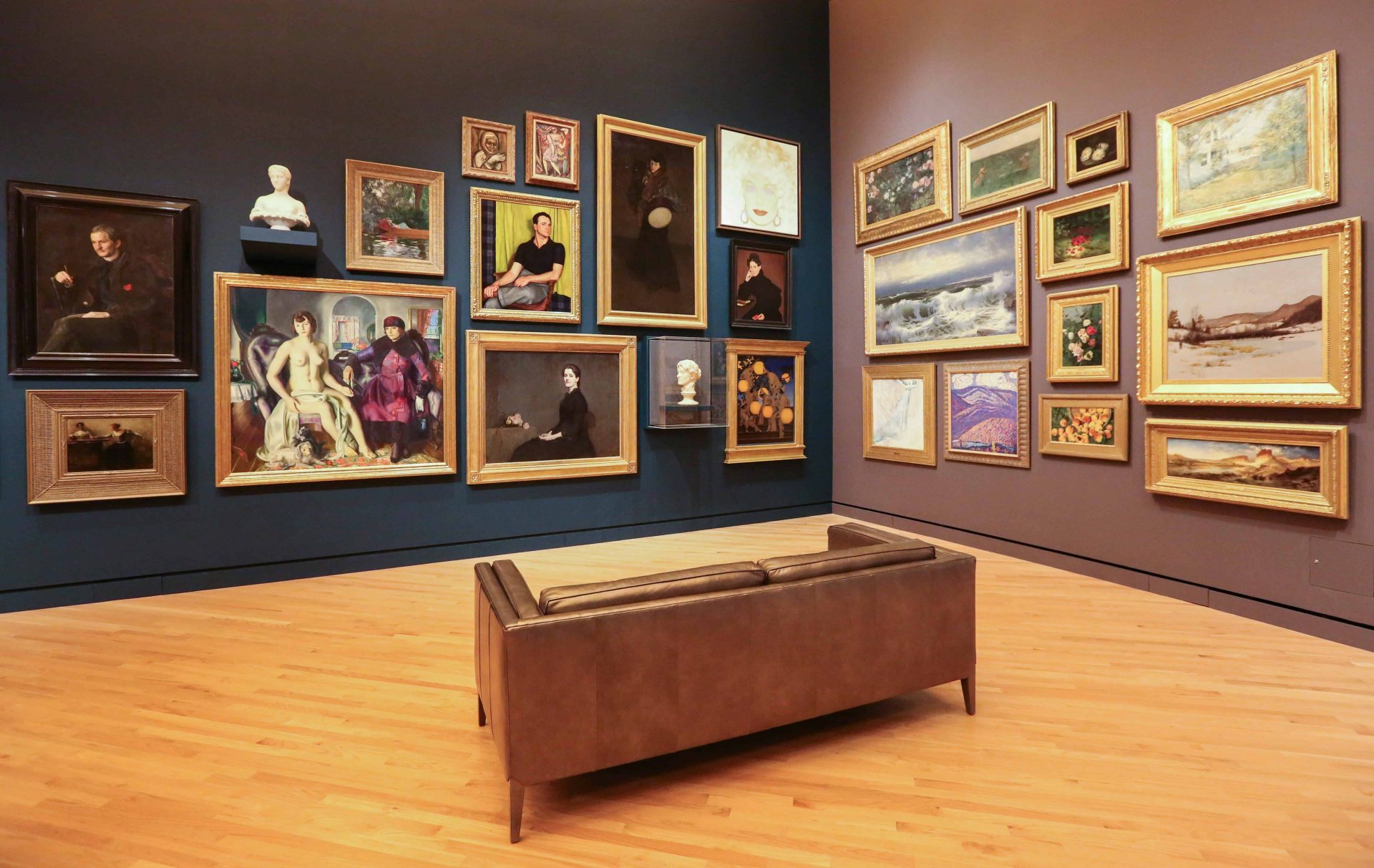 Museum gallery displaying framed paintings and sculptures on exhibition walls.